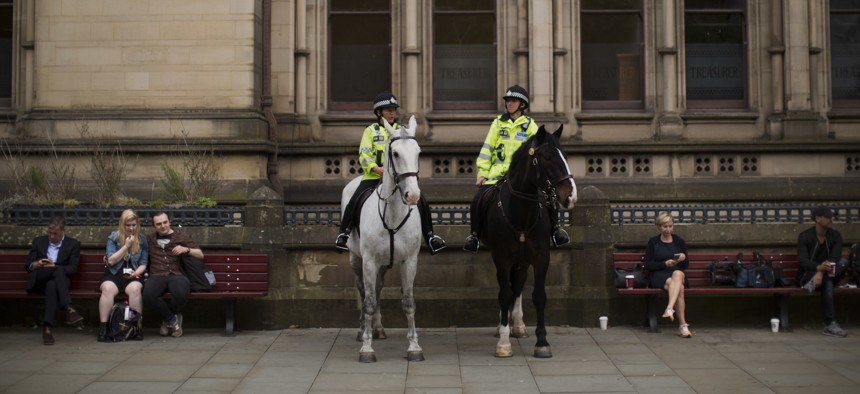 Mounted police officers keep watch as people place flowers in Albert Square in Manchester, Britain, Wednesday, May 24, 2017.