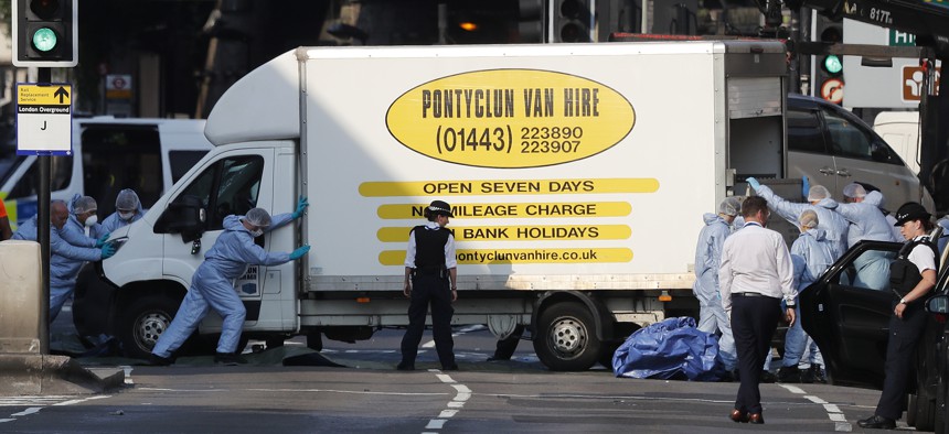Forensic officers move the van that struck pedestrians near a mosque in north London early Monday morning. 