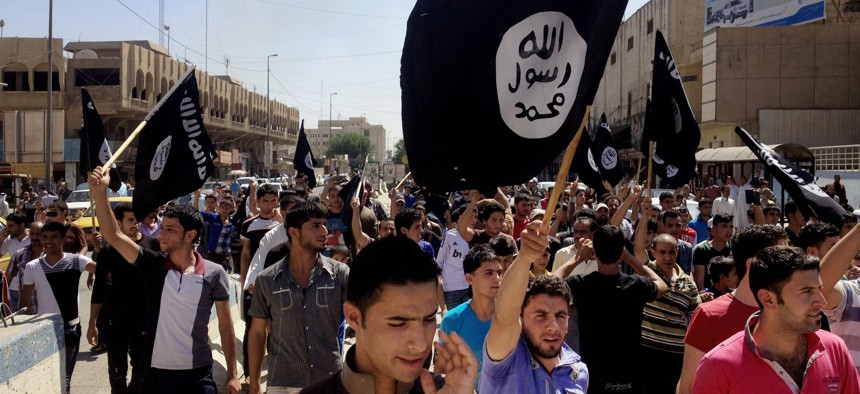  In this June 16, 2014 file photo, demonstrators chant pro-Islamic State group, slogans as they carry the group's flags in front of the provincial government headquarters in Mosul, 225 miles (360 kilometers) northwest of Baghdad. 
