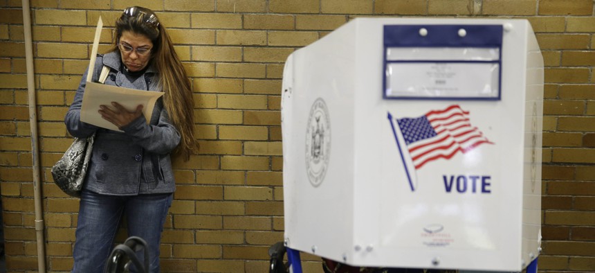 Because all the privacy booths are full, Miriam Rodriguez fills out her ballot while leaning against the wall at a polling site in New York, Tuesday, Nov. 4, 2014.