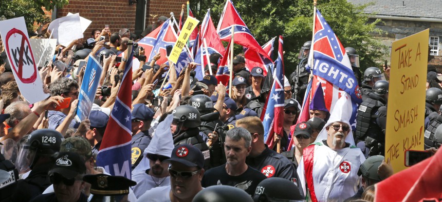 Members of the KKK are escorted by police past a large group of protesters during a KKK rally Saturday, July 8, 2017, in Charlottesville, Va.