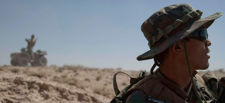 An Afghan special forces soldier scans the horizon as his American special forces counterpart reviews a map on an ATV in Kandahar province, June 2010.