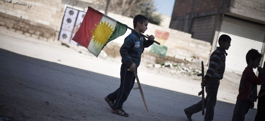 In this Monday, Feb. 26, 2013 file photo, a boy carries a Kurdish flag as he and others hold toy guns.
