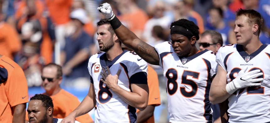 Denver Broncos tight end Virgil Green (85) gestures as teammate Max Garcia, left, takes a knee during the paying of the national anthem prior to an NFL football game against the Buffalo Bills, Sunday, Sept. 24, 2017, in Orchard Park, N.Y.
