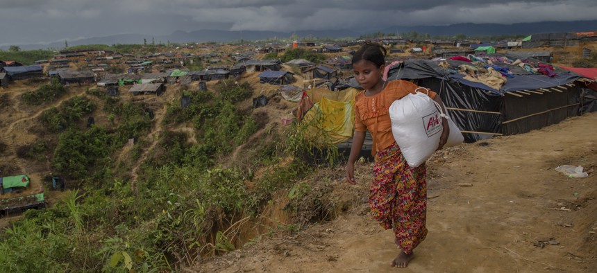 A Rohingya Muslim girl, who crossed over from Myanmar into Bangladesh, walks back to her shelter after collecting aid in Taiy Khali refugee camp, Bangladesh, Sept. 27, 2017.