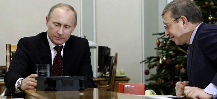 n this Tuesday, Dec. 28, 2010 file photo then Russian Prime Minister Vladimir Putin, left, holds a computer chip and a cell phone programmed to receive signals from Glonass.