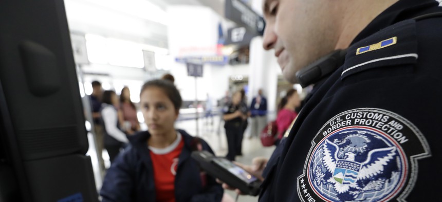A U.S. Customs and Border Protection officer helps a passenger navigate one of the new facial recognition kiosks at George Bush Intercontinental Airport, in Houston, July 12, 2017.