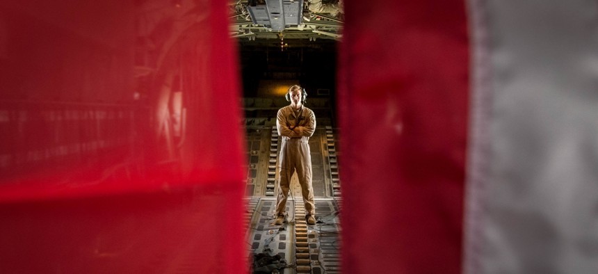 A U.S. Marine poses in between the U.S. Marine Corps flag and U.S. American flag in a KC-130J Super Hercules while forward deployed in the Middle East, Sept. 3, 2017.