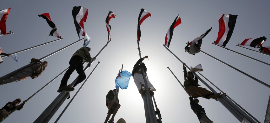 Supporters of Yemen's former President Ali Abdullah Saleh, who are allies of Shiite rebels known as Houthis, climb flag poles during a rally to mark the first anniversary of the Saudi-led military campaign against them, in Sanaa, Yemen, March 26, 2016.