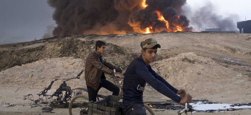 Iraqi youths ride bicycles next to a burning oil well in Qayara, about 31 miles (50 km) south of Mosul, Iraq, October 23, 2016.