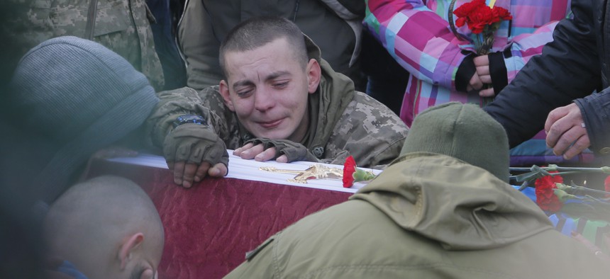 A comrade cries during the funeral ceremony for servicemen Sergey Kochetov and Nikolay Sayuk, Ukrainian volunteers from 'Aydar Battalion' who were killed in a war conflict in eastern Ukraine, at the Independence Square in Kiev, Ukraine. Nov 4. 2016.