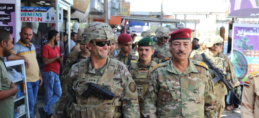 In this October photo, Lt. Gen. Paul Funk, left, commanding general of Combined Joint Task Force-Operation Inherent Resolve, and Iraqi Maj. Gen. Najm Abdullah al-Jibouri, right, walk through a busy market near the University of Mosul.