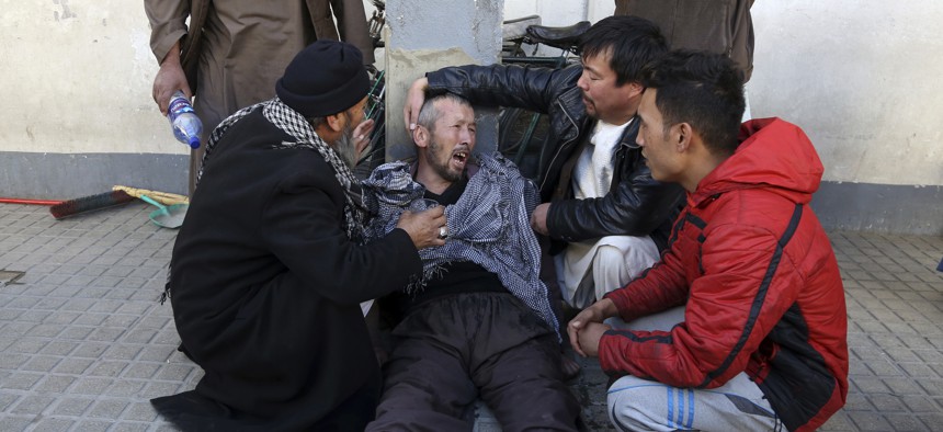A distraught man is cared for outside a hospital following a suicide attack in Kabul, Afghanistan, Thursday that killed dozens.