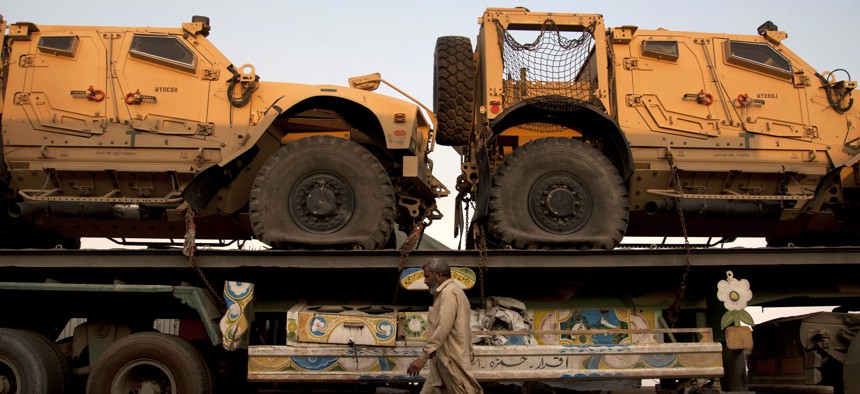 In this Nov. 26, 2013, file photo, a Pakistani man walks by a truck carrying NATO military vehicles at a terminal in Karachi, Pakistan.