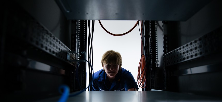 A U.S. Coast Guard officer peers through a space in a server at Coast Guard Base Boston, April 20, 2017. 