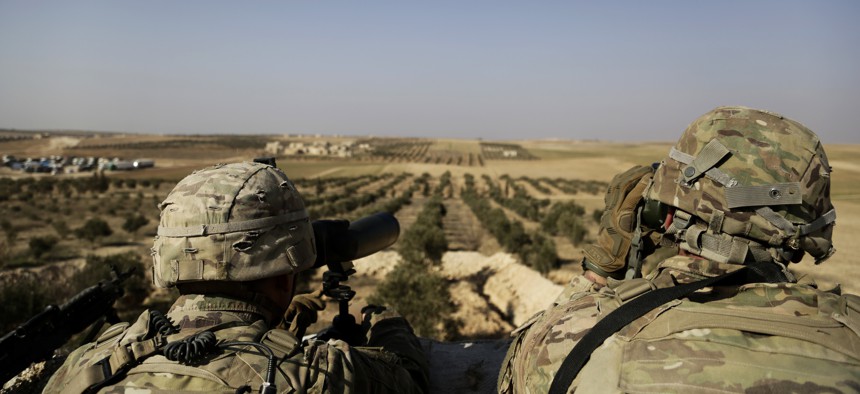 This Wednesday, Feb. 7, 2018 file photo, shows American troops looking toward the border with Turkey from a small outpost near the town of Manbij, northern Syria.