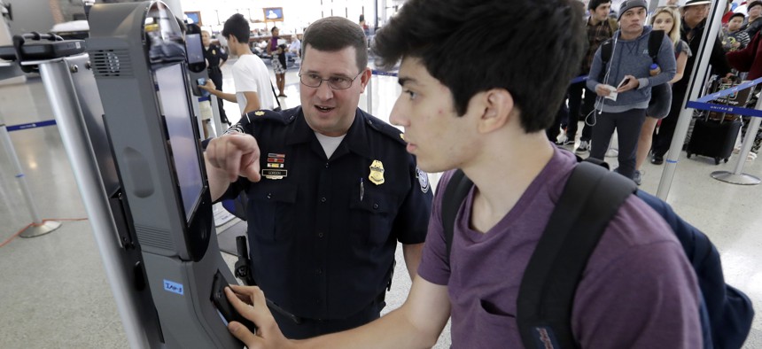 A U.S. Customs and Border Protection officer helps a passenger navigate one of the new facial recognition kiosks at a United Airlines gate at George Bush Intercontinental Airport, in Houston, July 12, 2017. 
