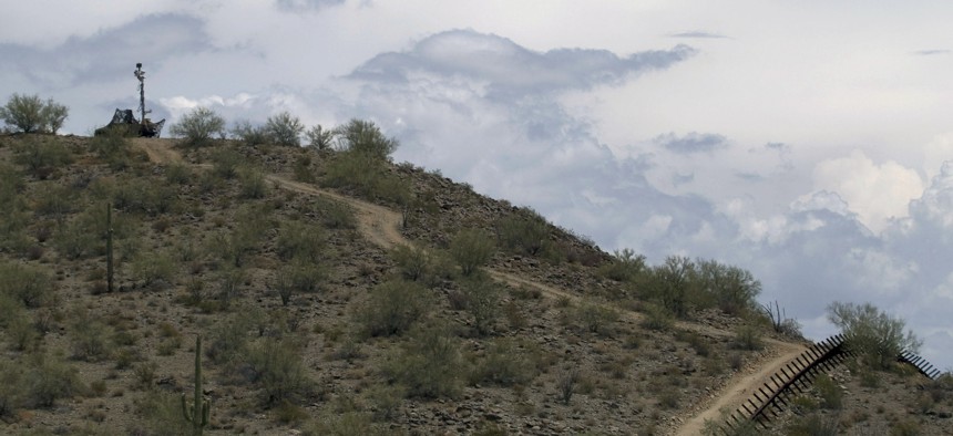 A US National Guard vehicle guards covered under camouflage fabric sits atop a mountain next to the border fence near Sonoyta, Mexico, Thursday, July 29, 2010. 