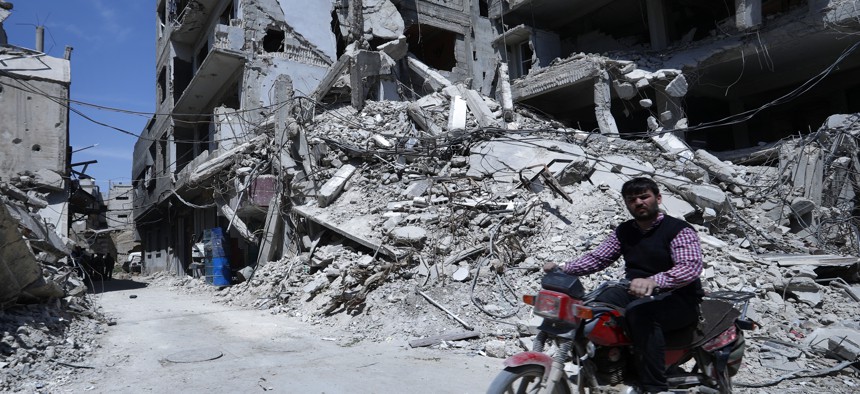 A man rides past destruction in the town of Douma, the site of a suspected chemical weapons attack, near Damascus, Syria, Monday, April 16, 2018. 