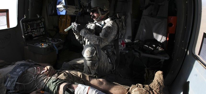 Airborne in a Black Hawk helicopter, U.S. Army flight medic Staff Sgt. Robert B. Cowdrey, of La Junta, Colo., with Charlie Company, All American Dustoff, attends to a U.S. Marine wounded in a rocket-propelled grenade attack, over Marjah, Helmand province,