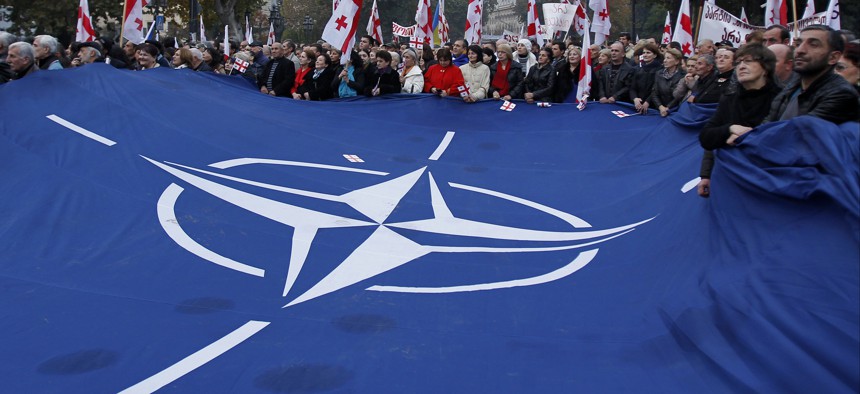 Demonstrators carry a huge banner with a NATO sign and Georgian national flags during a rally in Tbilisi, Georgia, on Nov. 15, 2014