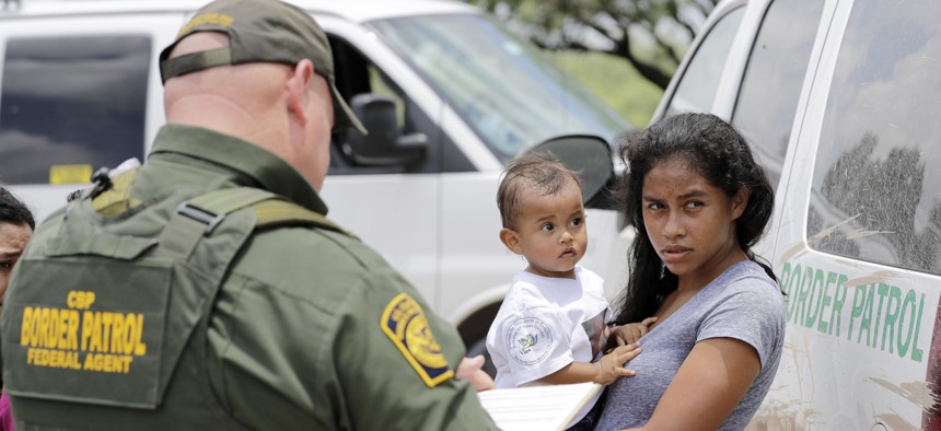 A mother migrating from Honduras holds her 1-year-old child as surrendering to U.S. Border Patrol agents after illegally crossing the border Monday, June 25, 2018, near McAllen, Texas. 