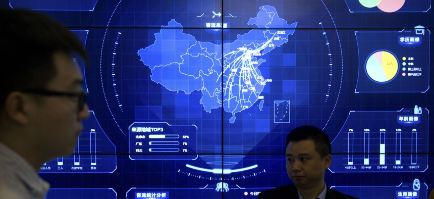 In this April 26, 2018, photo, visitors stand in front of an electronic data display showing a map of China at the Global Mobile Internet conference in Beijing.