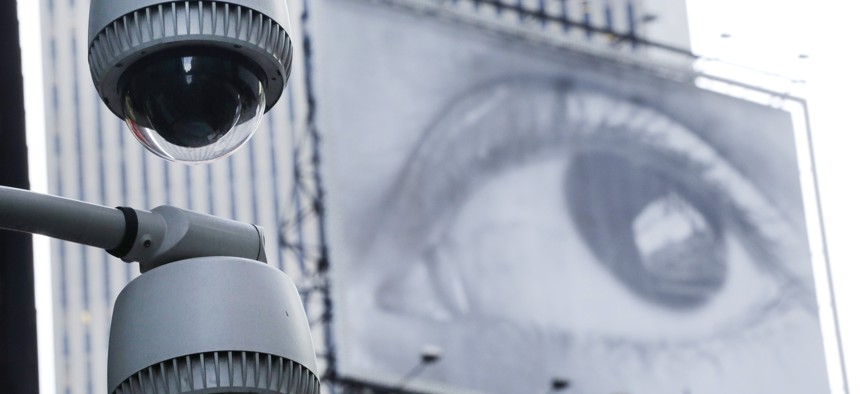 Security cameras are mounted on the side of a building overlooking an intersection in midtown Manhattan, Wednesday, July 31, 2013 in New York. In the background is a billboard of a human eye.