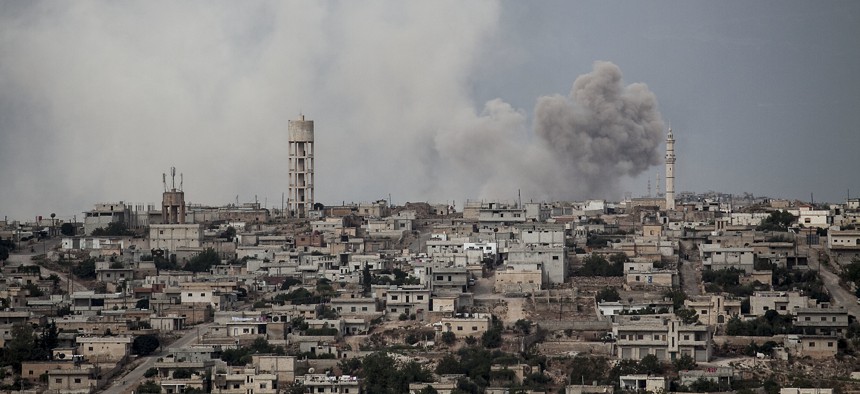 In this Sept. 19, 2013 photo, smoke rises after a TNT bomb was thrown from a helicopter, hitting a rebel position during heavy fighting between troops loyal to president Bashar Assad and opposition fighters, in the Idlib province countryside, Syria.