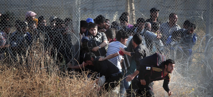 In this June 14, 2015  photo taken from the Turkish side of the border between Turkey and Syria, in southeastern Turkey, Syrian refugees burst into Turkey after breaking the border fence and crossing from Syria.