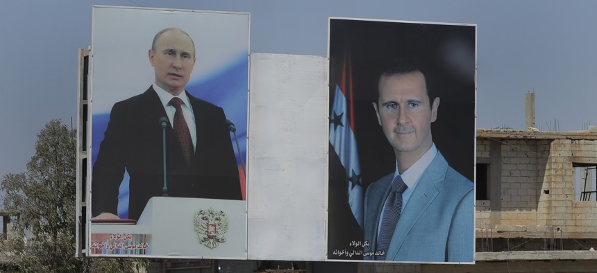 A local resident rides his motorcycle near portraits of Syrian President Bashar al-Asad, right, and Russian President Vladimir Putin in the town of Rastan, Syria, Wednesday, Aug. 15, 2018.