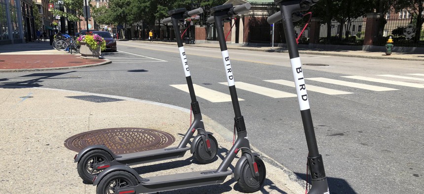 In this Friday, July 20, 2018 file photo, three dockless scooters stand on a sidewalk across the street from a Johnson & Wales University campus in downtown Providence, R.I. 