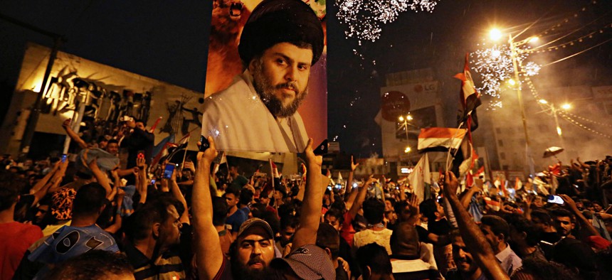 In this Monday, May 14, 2018 photo, supporters of Shiite cleric Muqtada al-Sadr, carry his image as they celebrate in Tahrir Square, Baghdad, Iraq.