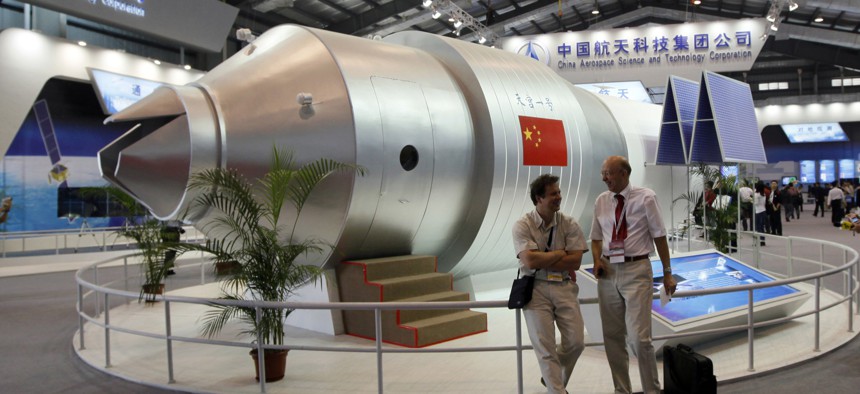 In this Nov. 16, 2010 file photo, visitors sit beside a model of China's Tiangong-1 space station at the 8th China International Aviation and Aerospace Exhibition in Zhuhai in southern China's Guangdong Province. 