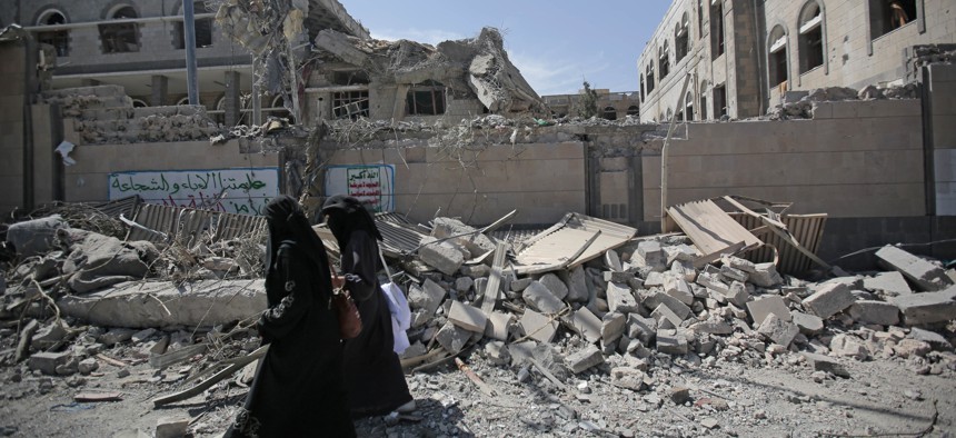 Yemenis walk past rubble after deadly airstrikes in and near the presidential compound, in Sanaa, Yemen, Monday, May. 7, 2018.