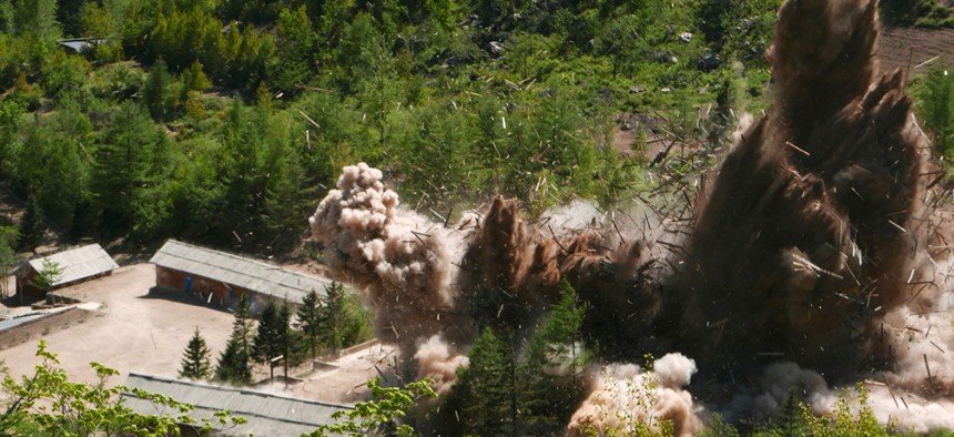 In this Thursday, May 24, 2018 photo, smoke and debris rise in the air as barracks buildings for guards and tunneling workers at North Korea's nuclear test site are blown up at Punggye-ri, North Hamgyong Province, North Korea
