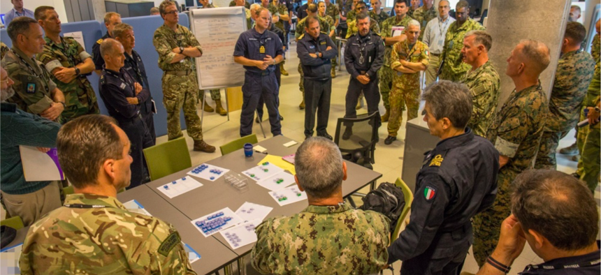 Participants of the Amphibious Leaders Expeditionary Symposium (ALES) gather around to discuss interoperability at NATO Joint Warfare Center in Stavanger, Norway, June 20, 2018. 