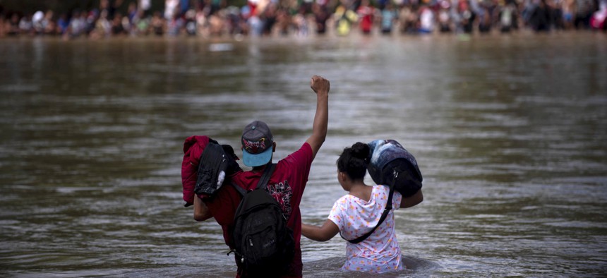 A migrant raises his fist as he nears the Mexican side of the the Suchiate River, that connects Guatemala and Mexico, Monday, Oct. 29, 2018.