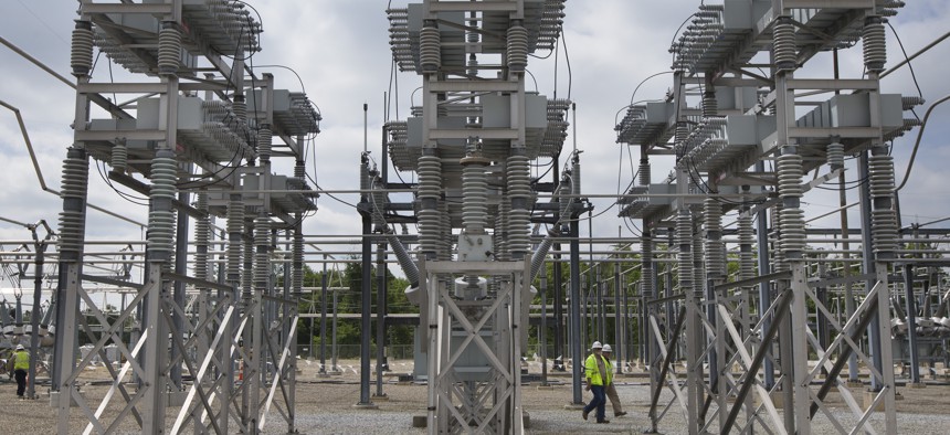 In this Wednesday, May 20, 2015 photo, contractors walk past a capacitor bank at an AEP electrical transmission substation in Westerville, Ohio. 