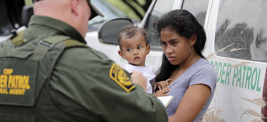 A mother migrating from Honduras holds her 1-year-old child as surrendering to U.S. Border Patrol agents after illegally crossing the border Monday, June 25, 2018, near McAllen, Texas.