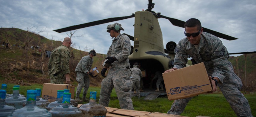 U.S. service members stack boxes of aid which and water while off loading a U.S. Army CH-47 Chinook during an aid relief mission Oct. 14, 2016, in Anse d'Hainault, Haiti.