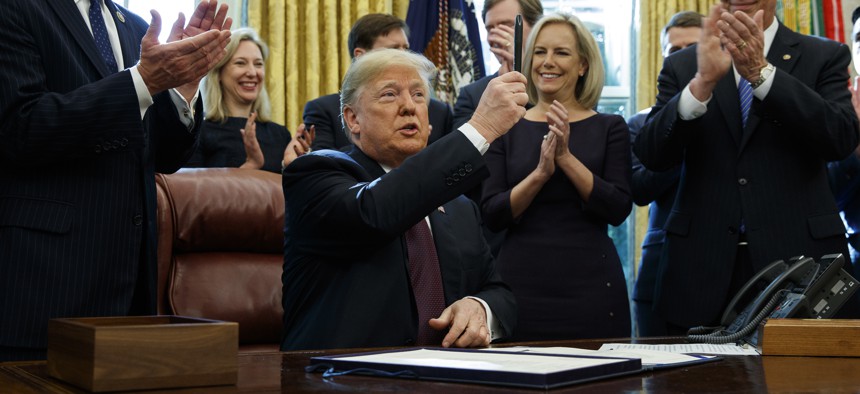 President Donald Trump holds up a pen during a signing ceremony of the "Cybersecurity and Infrastructure Security Agency Act," in the Oval Office of the White House, Friday, Nov. 16, 2018, in Washington.