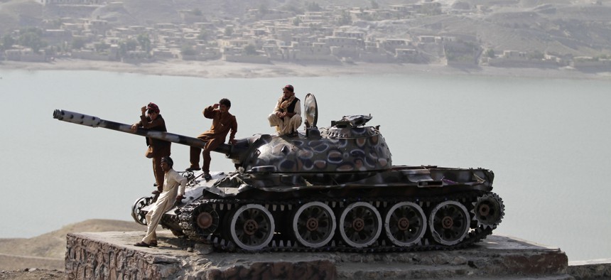 Afghan men sit on top of an old Soviet tank overlooking Naghlu lake on the outskirts of Kabul, Afghanistan, Thursday, Sept. 11, 2013.