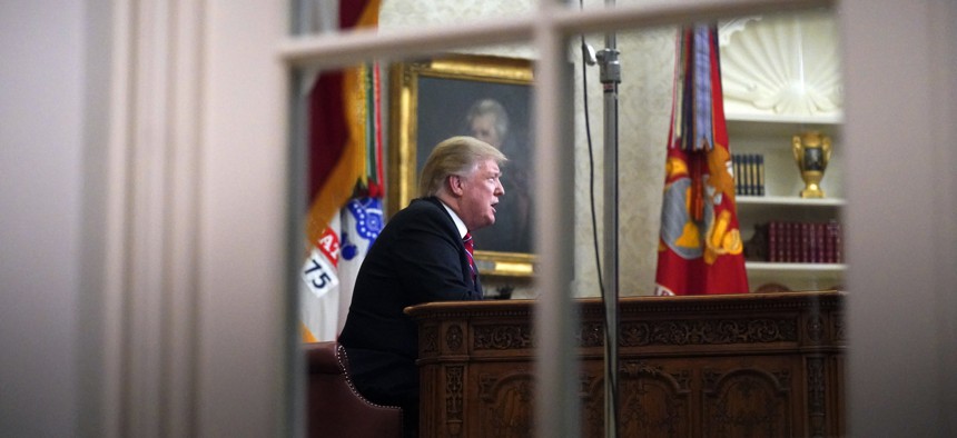 As seen from a window outside the Oval Office, President Donald Trump gives a prime-time address about border security Tuesday, Jan. 8, 2018, at the White House in Washington.