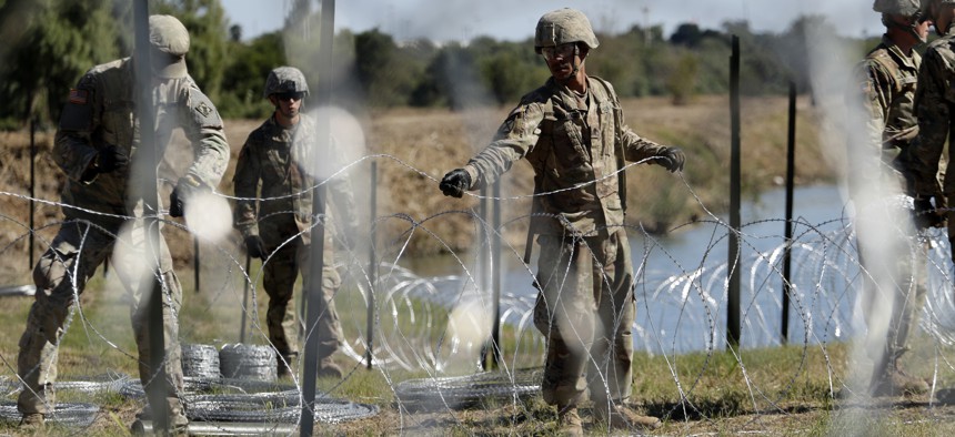 In this Nov. 16, 2018, photo, members of the U.S. military install multiple tiers of concertina wire along the banks of the Rio Grande near the Juarez-Lincoln Bridge at the U.S.-Mexico border in Laredo, Texas.