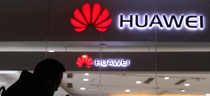 A man lights a cigarette outside a Huawei retail shop in Beijing Thursday, Dec. 6, 2018. China on Thursday demanded Canada release a Huawei Technologies executive who was arrested in a case that adds to technology tensions with Washington.