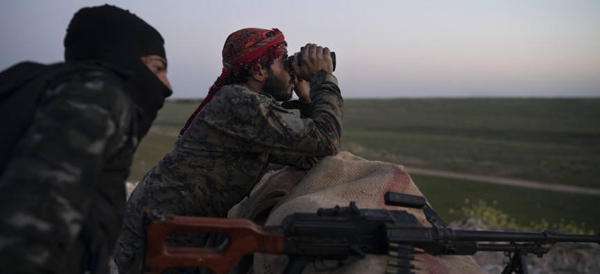 U.S.-backed Syrian Democratic Forces (SDF) fighters watch as an airstrike hits territory still held by Islamic State militants in the desert outside Baghouz, Syria, Tuesday, Feb. 19, 2019.