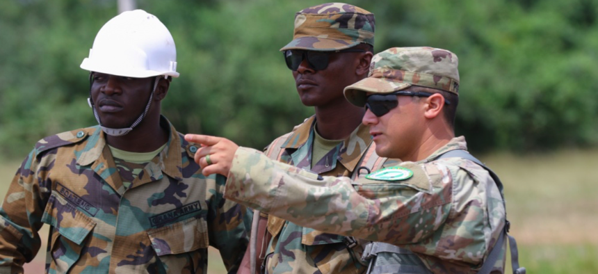 Sgt. Jose Portugal, a technical engineer assigned to Headquarters and Headquarters Company, 64th Engineer Battalion, 36th Engineer Brigade, discusses engineering methods with Ghanaian Army engineers at the Bundase Training Camp outside Accra, Ghana.