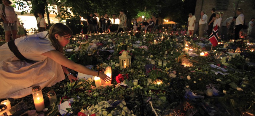 A woman lights candles among flowers and tributes laid outside the Oslo Cathedral in Oslo, Norway in memory of the victims of July 22 bomb attack and shooting rampage, late Sunday, July 31, 2011.