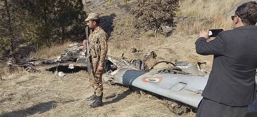 A Pakistani soldier stands guard near the wreckage of an Indian plane shot down by the Pakistan military on Wednesday, in Hurran, near the Line of Control in Pakistani Kashmir, Thursday, Feb. 28, 2019,